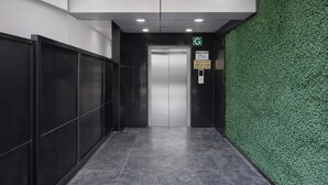 Un pasillo con una pared verde, una puerta y un cartel que indica un ascensor.