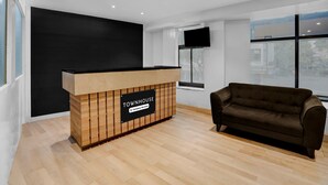 Un mostrador de recepción con el rótulo 'TOWNHOUSE', diseño moderno, un sofá y amplias ventanas.