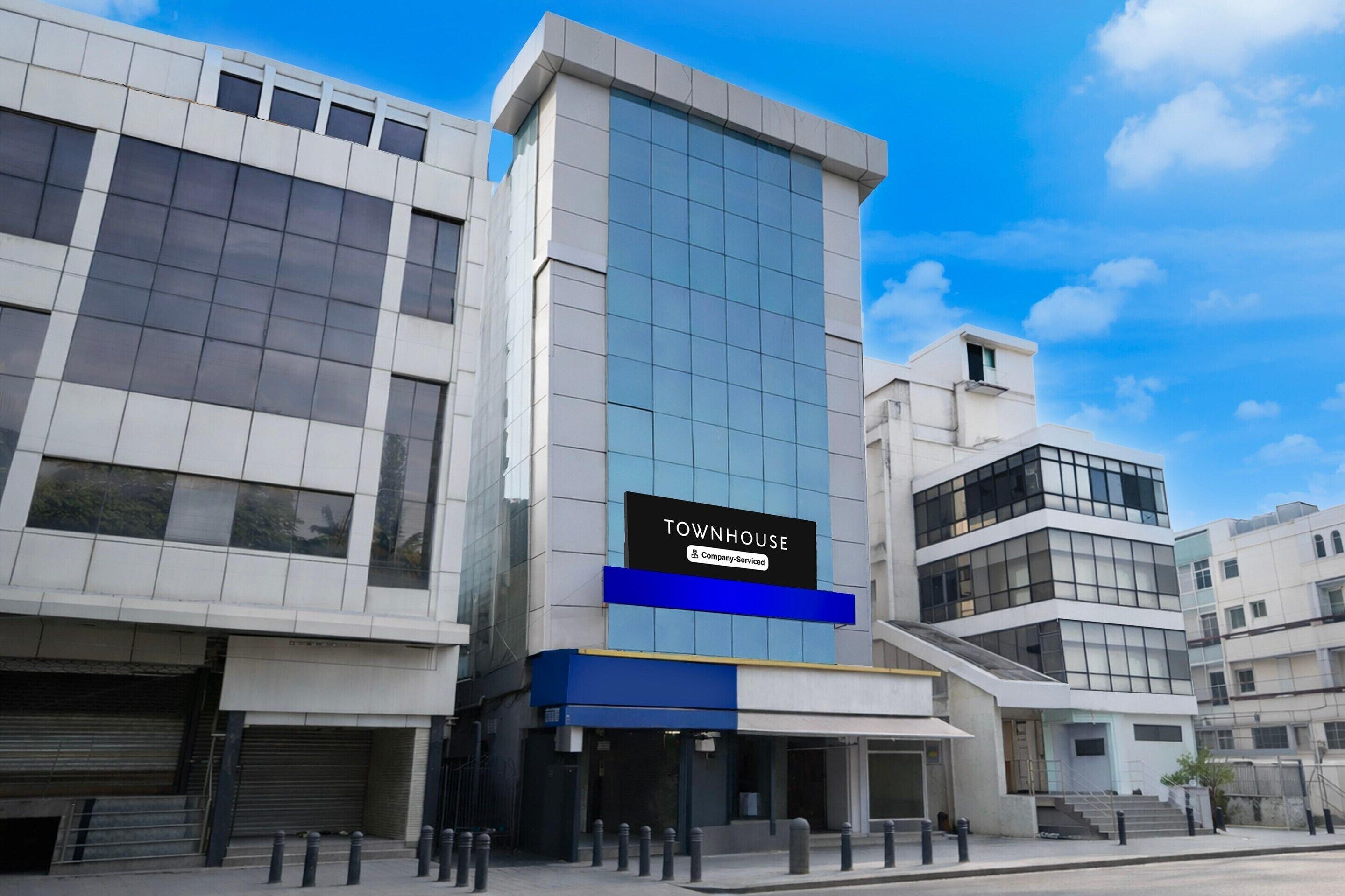 Een modern gebouw met een bord waarop 'TOWNHOUSE' staat en een label dat aangeeft dat het door een bedrijf wordt beheerd.