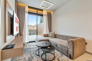 Ein modernes Wohnzimmer mit einer Couch, einem Couchtisch, einem Fernseher und Blick auf Gebäude.