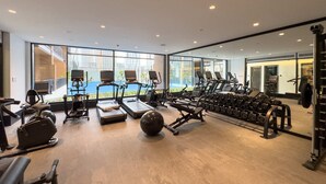 A gym with treadmills, dumbbells, and exercise equipment. - Free Housekeeping Visits During Your Stay - Stayshort - Fresh 2 Bedroom Apartment in JVC That Sleeps 5 (Dubai)