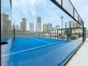 A rooftop tennis court with a city skyline in the background. - Free Housekeeping Visits During Your Stay - Stayshort - Fresh 2 Bedroom Apartment in JVC That Sleeps 5 (Dubai)