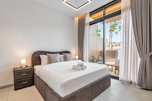A modern hotel room with a large bed, a nightstand, and a view of the outdoors. - Free Housekeeping Visits During Your Stay - Stayshort - Fresh 2 Bedroom Apartment in JVC That Sleeps 5 (Dubai)
