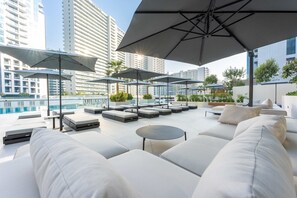 A rooftop lounge with outdoor seating, umbrellas, and a pool view. - Free Housekeeping Visits During Your Stay - Stayshort - Modern 3 Bedroom in Business Bay That Sleeps 6 (Dubai)