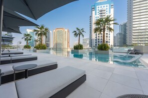 A rooftop pool area with lounge seating and palm trees. - Free Housekeeping Visits During Your Stay - Stayshort - Modern 3 Bedroom in Business Bay That Sleeps 6 (Dubai)