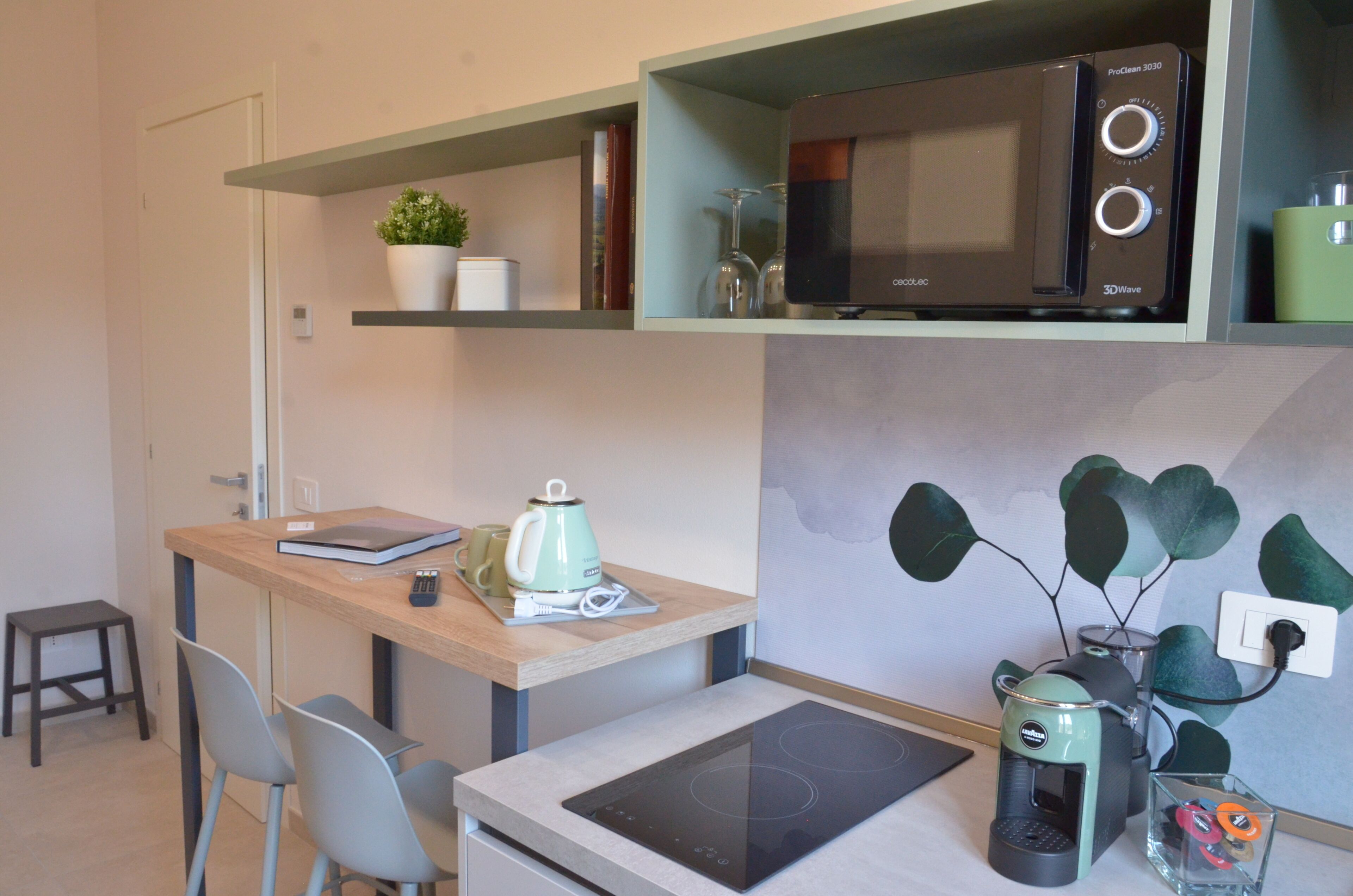 A compact kitchenette with a microwave, coffee maker, and induction cooktop.
