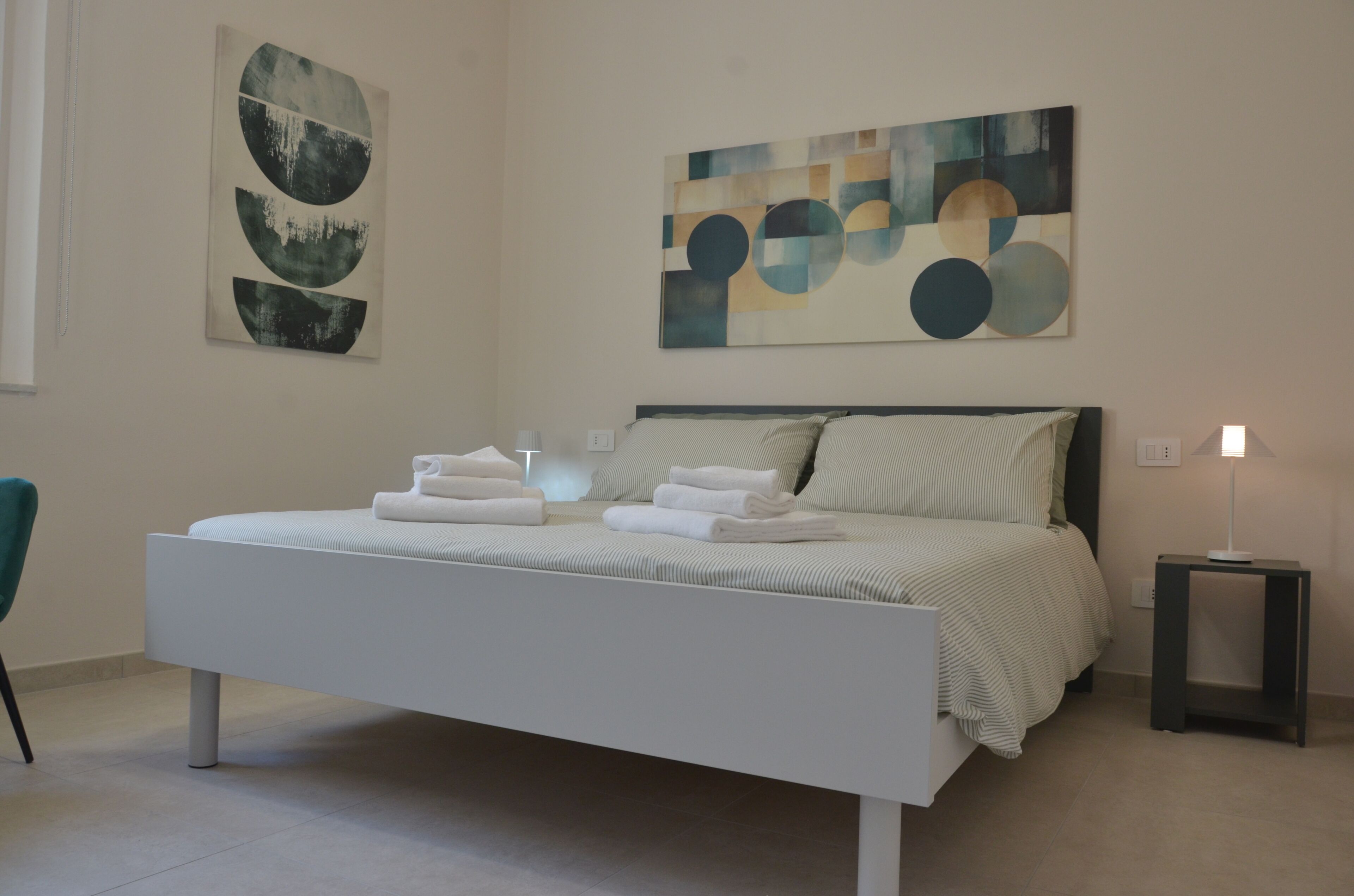 Un dormitorio moderno con una cama grande, una mesita de noche y arte abstracto en la pared.