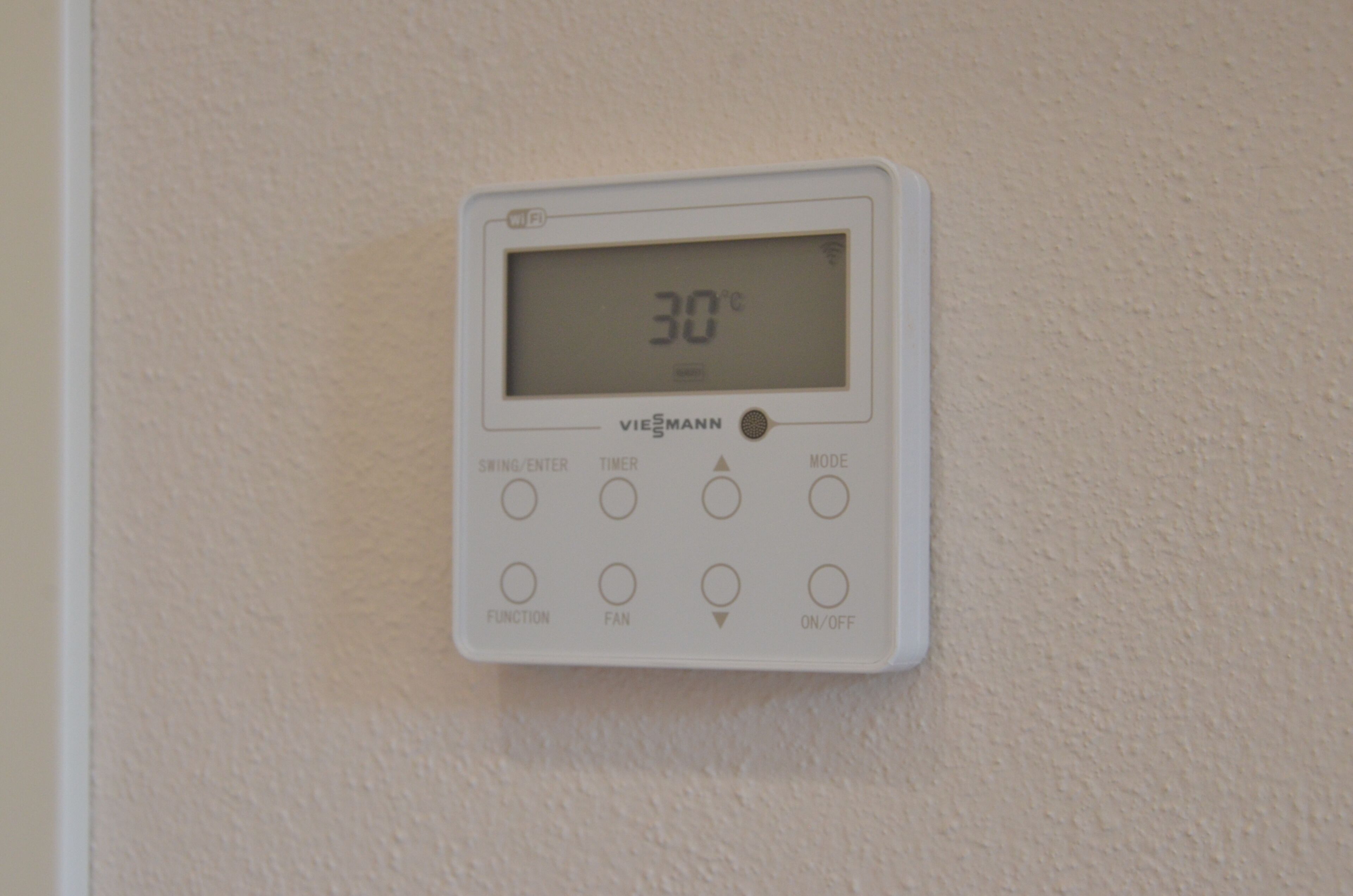 Un thermostat mural blanc doté d’un écran numérique indiquant 30 °C, portant la mention « VIEßMANN ».