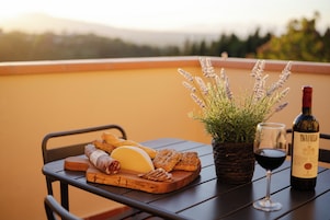 A table with a cheese board, bread, a bottle of wine, and a potted plant.