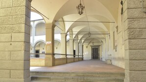 Ein Korridor mit steinernen Säulen, einer Treppe und einem hängenden Laternenleuchter.