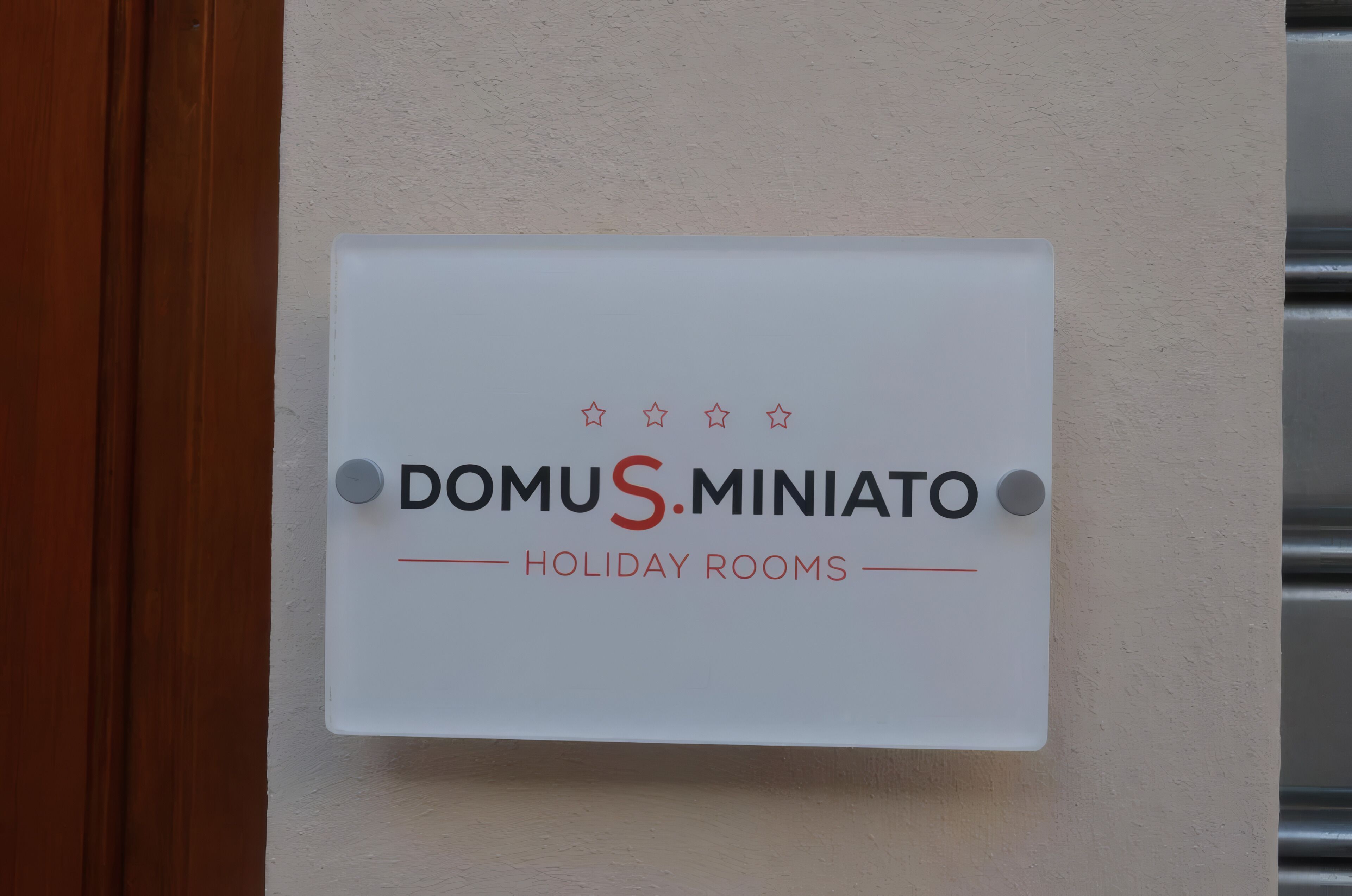 Un cartel que indica 'DOMUS MINIATO HOLIDAY ROOMS' en una pared.