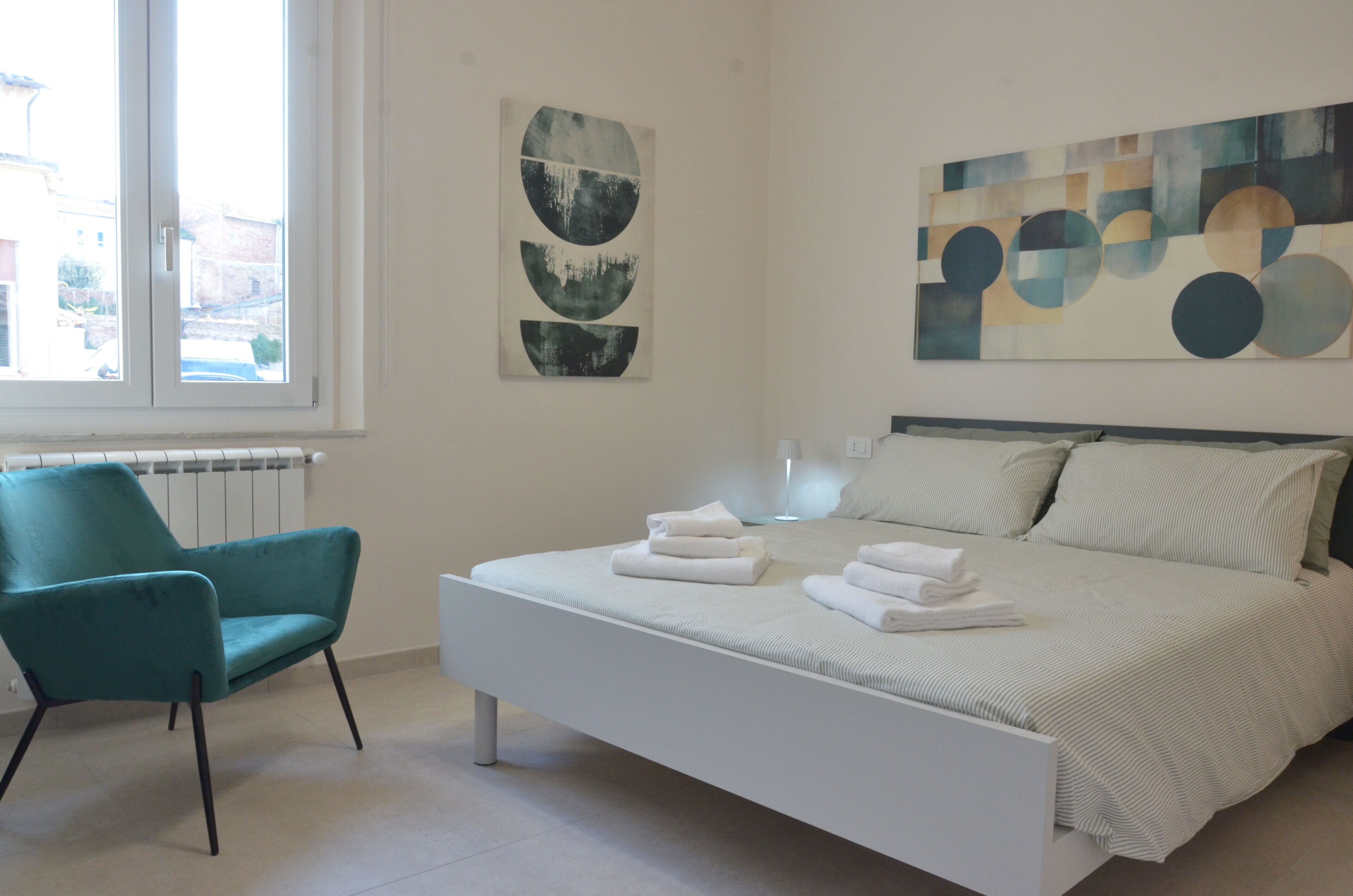 A modern bedroom with a bed, a chair, and artwork on the walls.