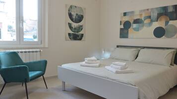 A modern bedroom with a bed, a chair, and artwork on the walls.
