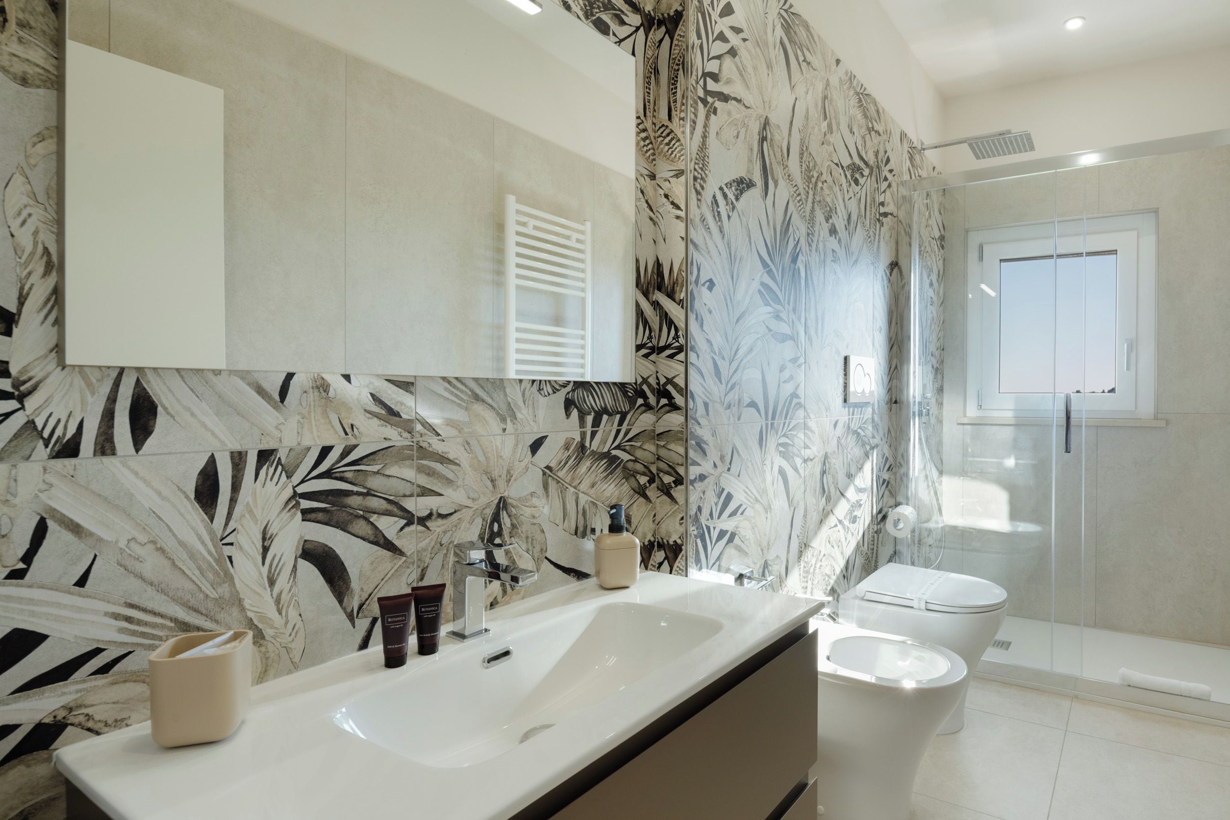 Ein Badezimmer mit einem großen Spiegel, zwei Waschbecken, einer Toilette und einer Dusche.
