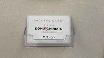 Un lector de tarjetas con una luz azul, una ranura para tarjetas y un cartel que dice 'DOMUS MINIATO HOLIDAY ROOMS Il Bargo'.