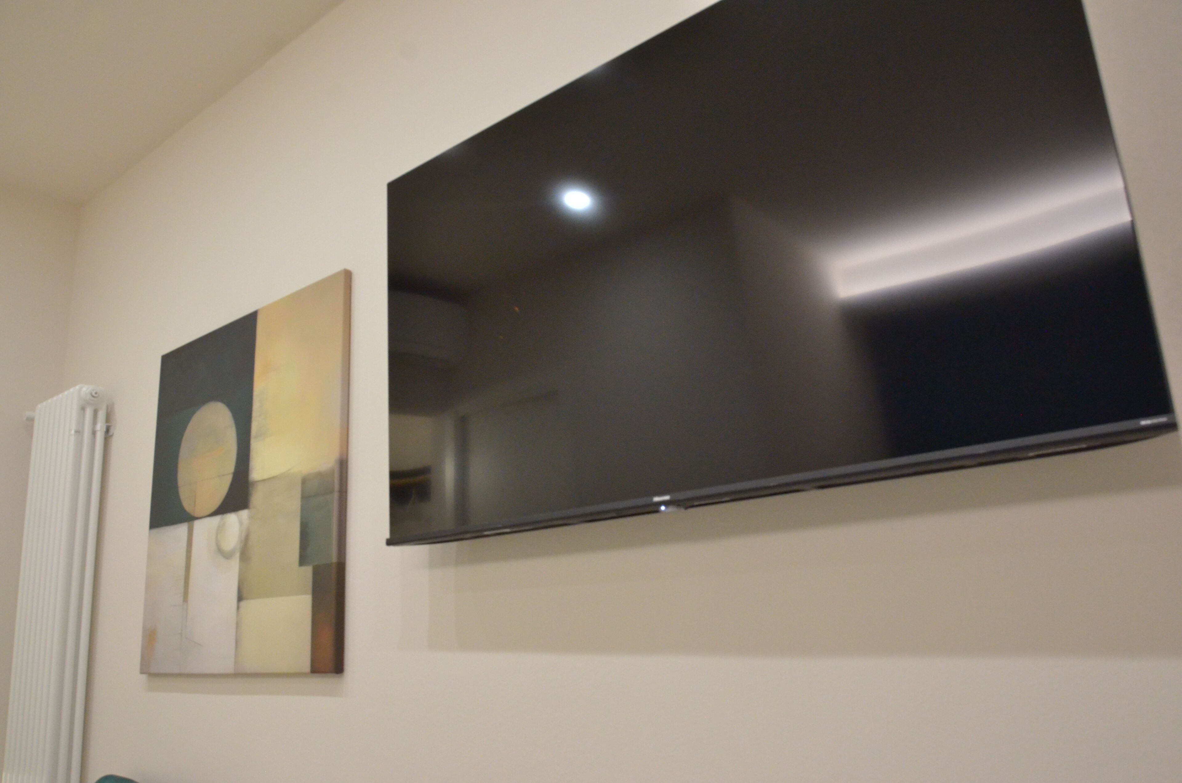 A wall-mounted flat-screen TV and a piece of abstract art.