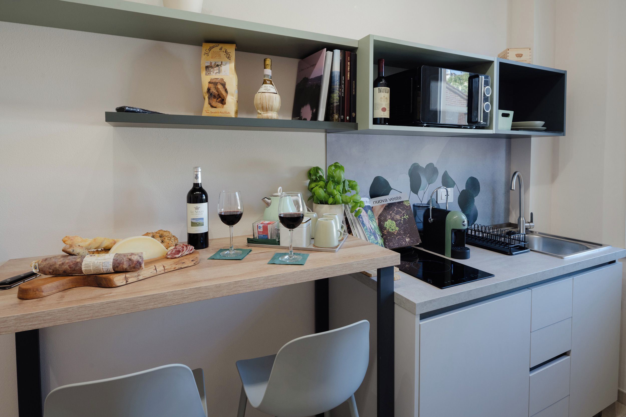 A modern kitchen with a wooden countertop, wine bottles, a coffee machine, and a sink.