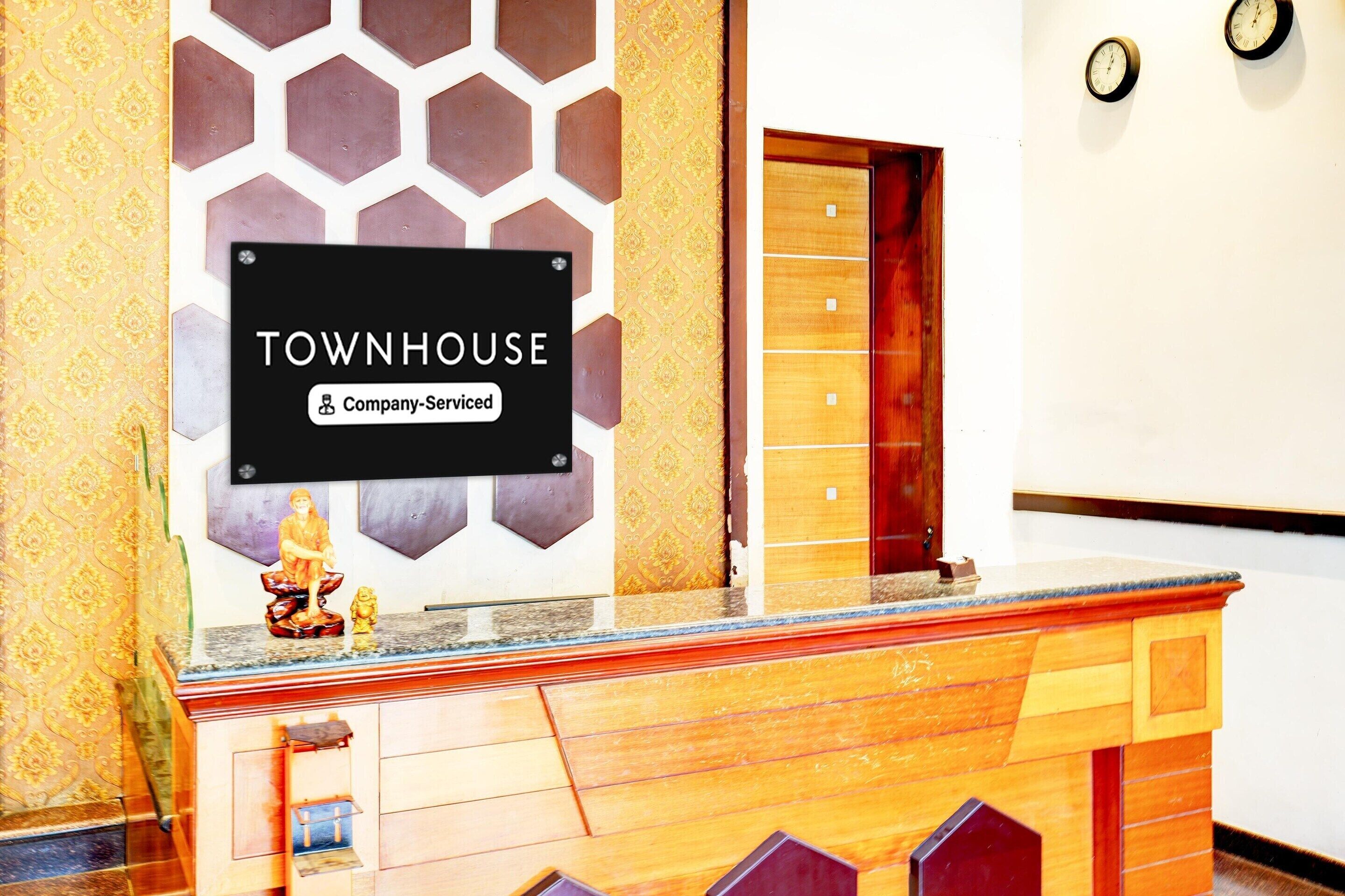 A reception desk with a 'TOWNHOUSE' sign, a wooden counter, and a patterned wall behind it.