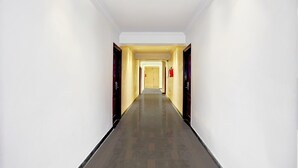 Un pasillo largo y estrecho con suelo reflectante, paredes blancas y puertas a ambos lados.