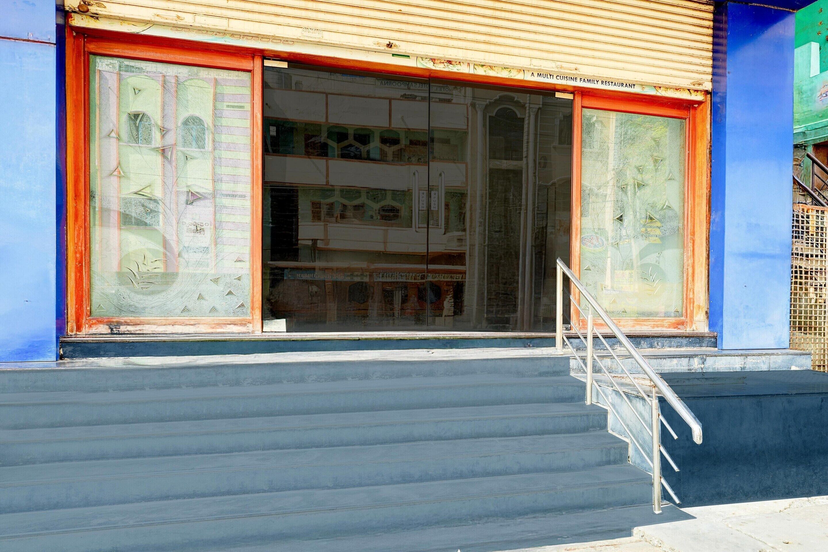 Ein Gebäude mit einer Treppe, die zu einer Tür mit Glastürflügeln führt.