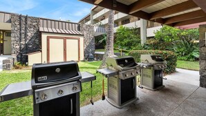 Un patio al aire libre con dos parrillas de gas Weber Spirit y un muro de piedra.