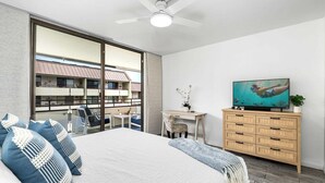 Un dormitorio con una cama grande, un escritorio, un televisor y vistas a un edificio.