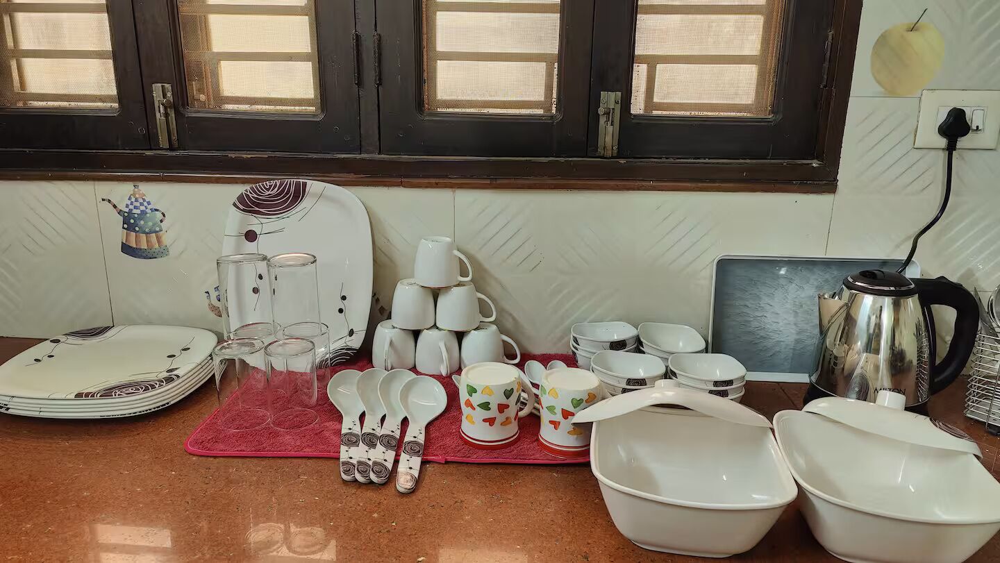 A kitchen counter with various white dishes, including plates, bowls, and cups, arranged on a red mat.