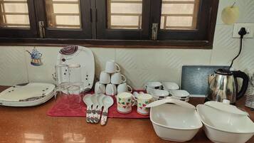 A kitchen counter with various white dishes, including plates, bowls, and cups, arranged on a red mat.