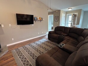 A living room with a sectional sofa, a flat-screen TV mounted on the wall, and a patterned rug. - Stargazer Paradise- Located in Livingston with a yard! (Livingston)