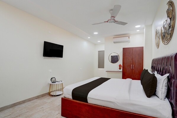 A bedroom with a bed, a ceiling fan, a TV, a wardrobe, and a small table with a kettle. - Deluxe The Paradise Guest Inn (Nellore)