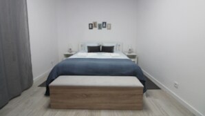 Una camera da letto con un letto, comodini, una panca e quadri appesi al muro.