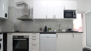 Una cucina moderna con mobili bianchi, lavastoviglie, forno, microonde e cappa aspirante in acciaio inossidabile.