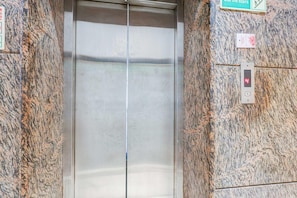 An elevator with a digital display showing the number 4, surrounded by granite walls.