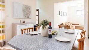 A dining area with a granite table, a bottle of wine, and a potted plant. - budget apartment, affordable stay, cozy apartment, family friendly, group accommodation, patio apartment, outdoor space, free wifi, smart TV, kitchen, central location, value stay, comfortable stay (Il-Mellieħa)