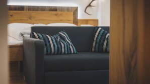 Un canapé de couleur sombre agrémenté de coussins à rayures, une tête de lit en bois et une décoration murale représentant des bois de cerf.