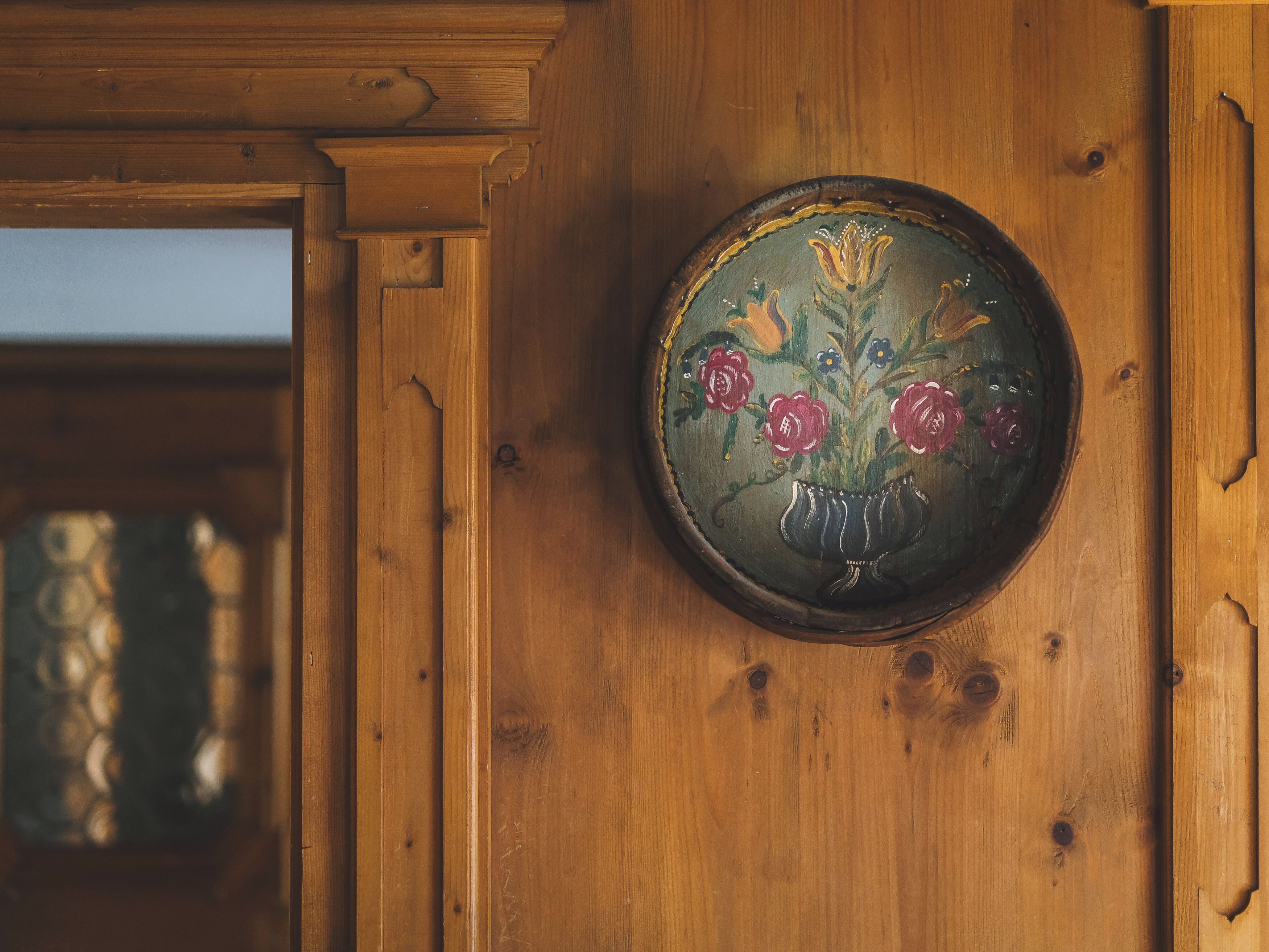 Une porte en bois ornée d’une plaque circulaire en laiton représentant un motif floral.