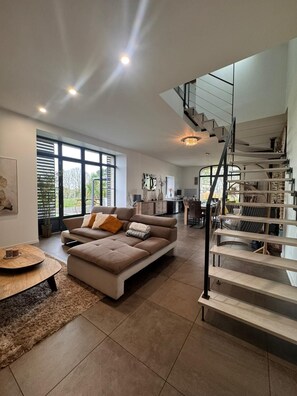 Ein modernes Wohnzimmer mit einer Couch, einem Couchtisch und einer Treppe.