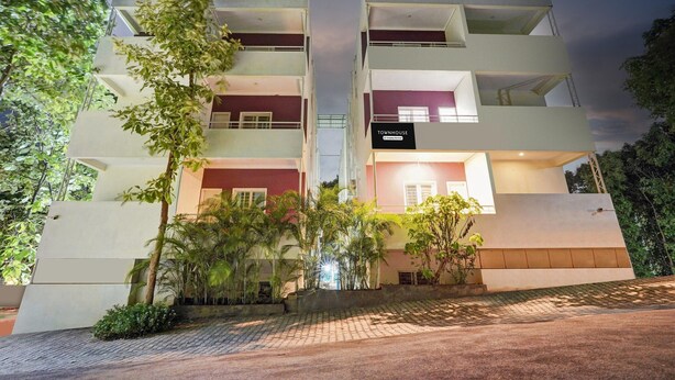 A multi-story building with balconies, a sign reading 'Townhouse,' and surrounding greenery. - Deluxe Hebbal Mysore Green Orchid Resort (Mysore)