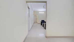 A hallway with a ceiling fan, a reception desk, and a door at the end. - Deluxe Hebbal Mysore Green Orchid Resort (Mysore)