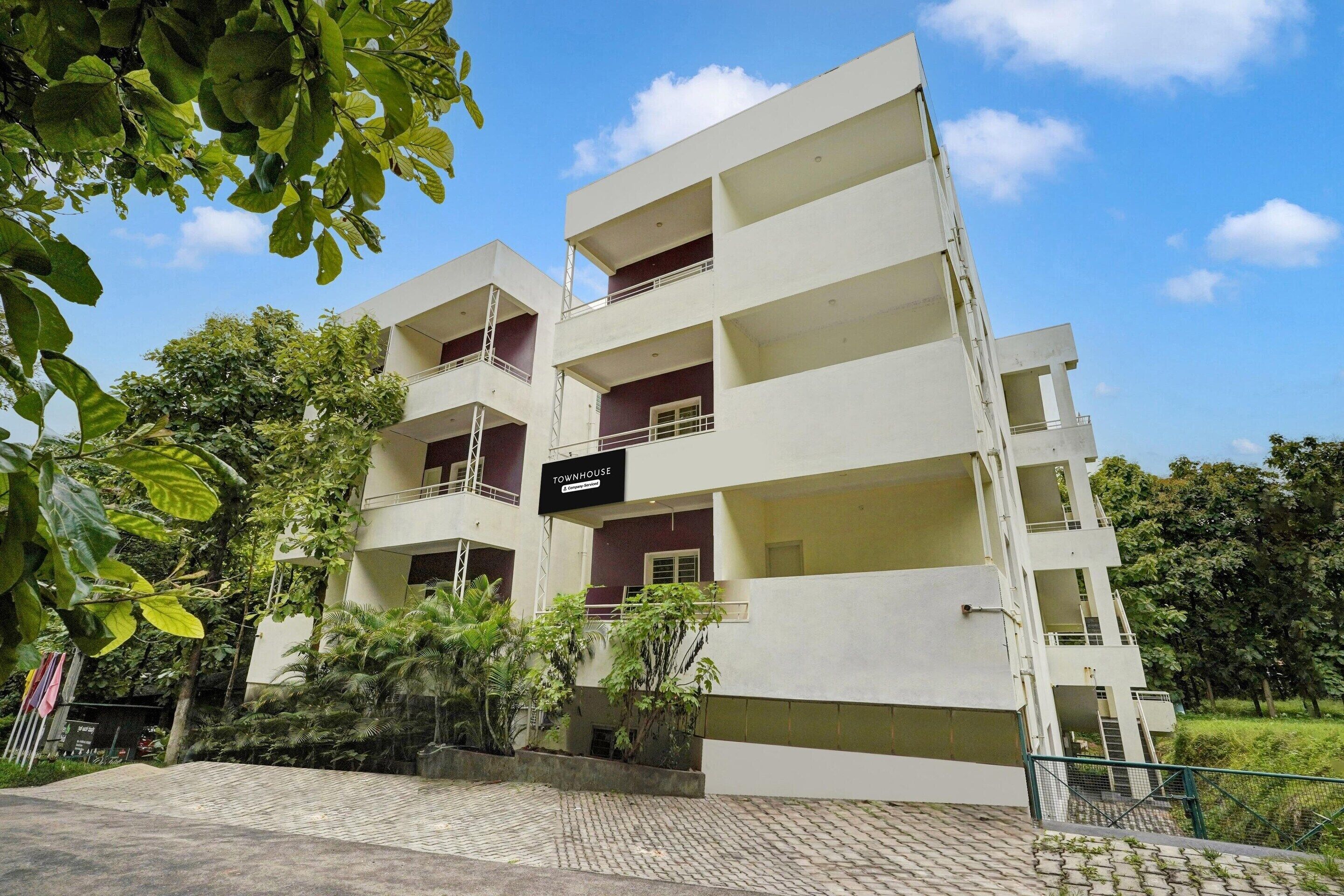 A multi-story building with balconies, a sign reading 'Townhouse,' and surrounding greenery.