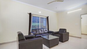 A living room with a sofa set, a coffee table, and a ceiling fan. - Deluxe Hebbal Mysore Green Orchid Resort (Mysore)