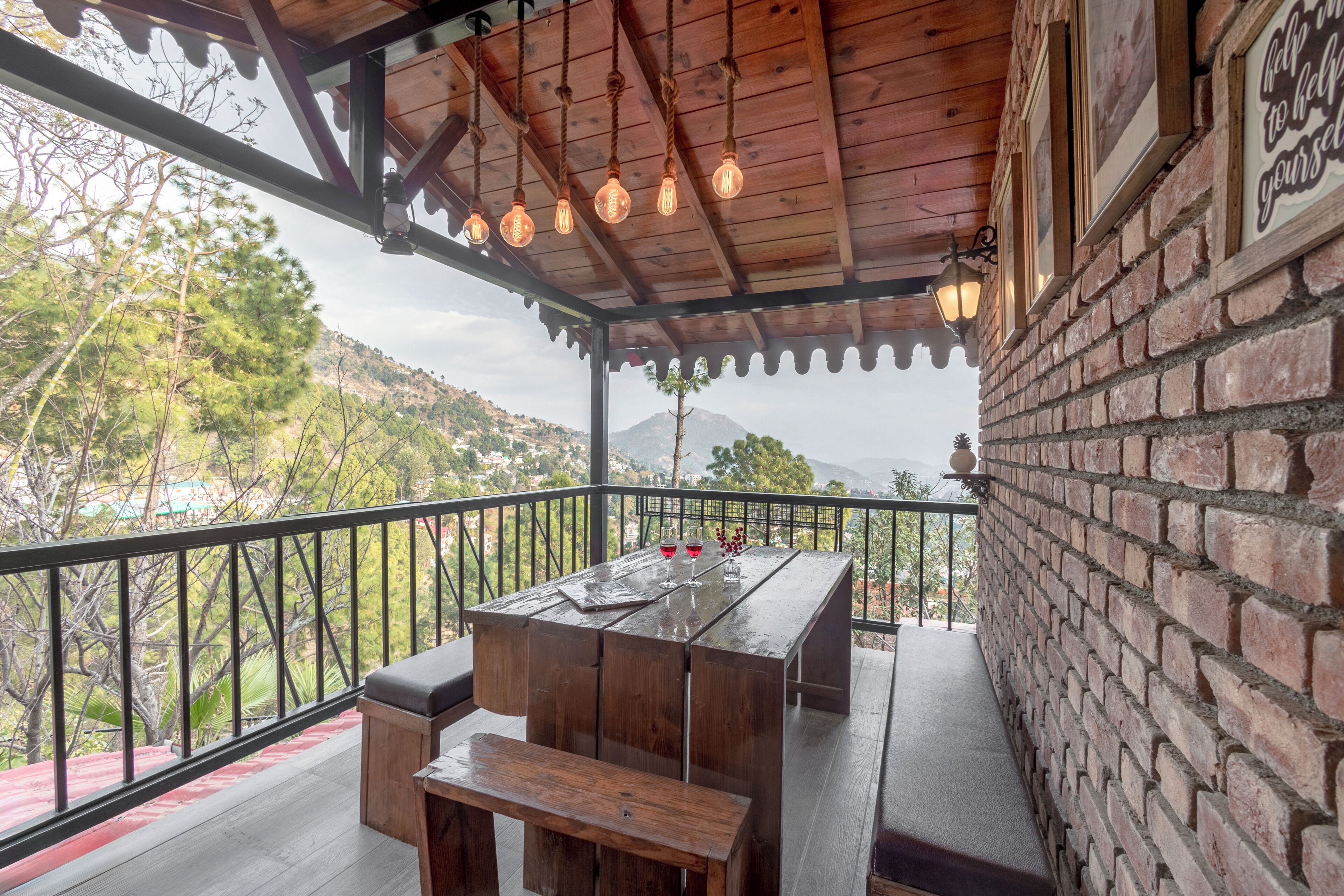 A wooden deck with a table and bench, a brick wall, and a view of trees and mountains.