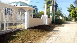 Una entrada cerrada con cerca blanca y un edificio con ventanas arqueadas.