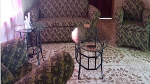 Una sala de estar con sofás estampados, una mesa de centro de vidrio y una alfombra con diseño.