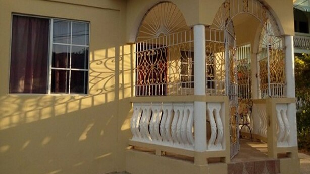Un edificio con balcón, ventana y puerta con detalles de metalería.