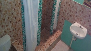 Un baño con inodoro, zona de ducha con cortinas y lavamanos.