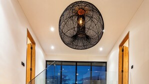 A modern interior with a glass staircase, a pool, and a large ceiling light fixture. - Villa Balinese Elite Sanctuary (Ubud)