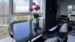 A modern dining area with a black table, two chairs, and a vase of purple flowers. - Hive Loft 2BR BGC w/ Free Parking + Skyline View (Taguig)
