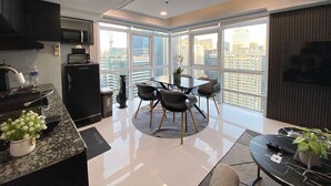 A modern kitchen with a dining area, large windows, and a city view. - Hive Loft 2BR BGC w/ Free Parking + Skyline View (Taguig)