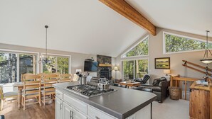 A spacious kitchen with a central island, wooden dining set, and a cozy seating area with a fireplace.